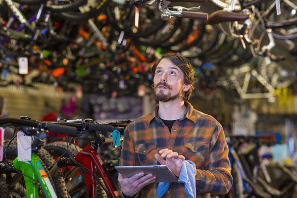 Caucasian worker using digital tablet in bicycle shop