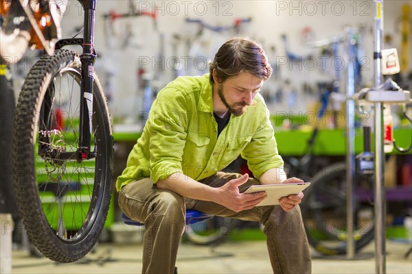 Caucasian worker using digital tablet in bicycle shop