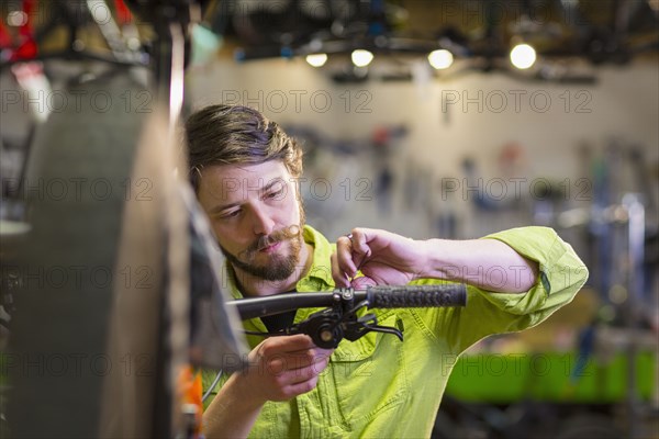 Caucasian worker repairing bicycle handlebar in shop