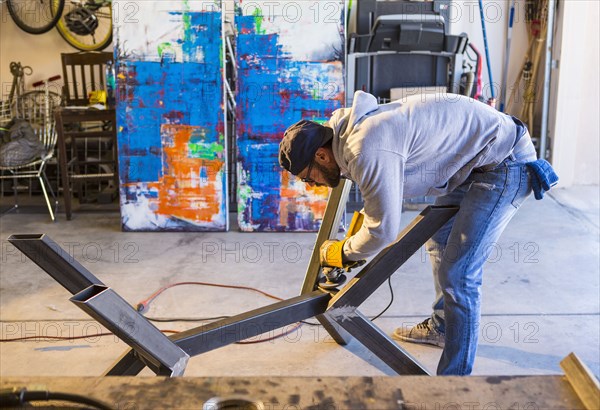 Caucasian man grinding metal sculpture