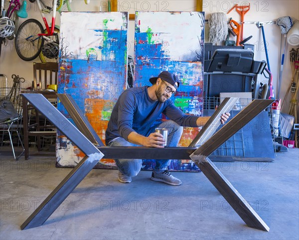 Caucasian man crouching and examining metal sculpture