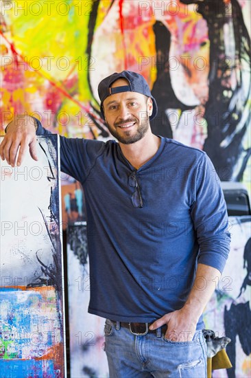 Portrait of Caucasian man leaning on painting