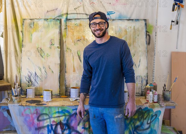 Portrait of Caucasian man standing near paintings