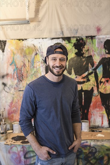 Portrait of Caucasian man standing near paintings