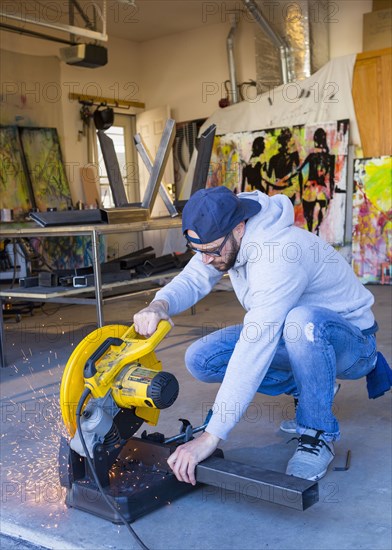 Caucasian man cutting metal with saw