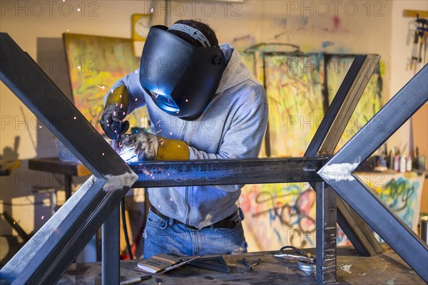 Caucasian man welding metal sculpture