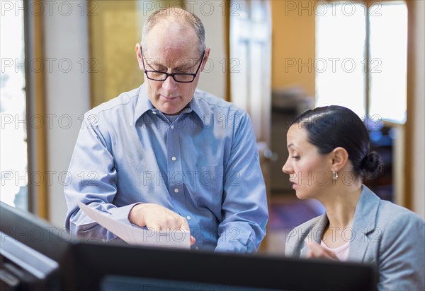 Caucasian business reading paperwork in office