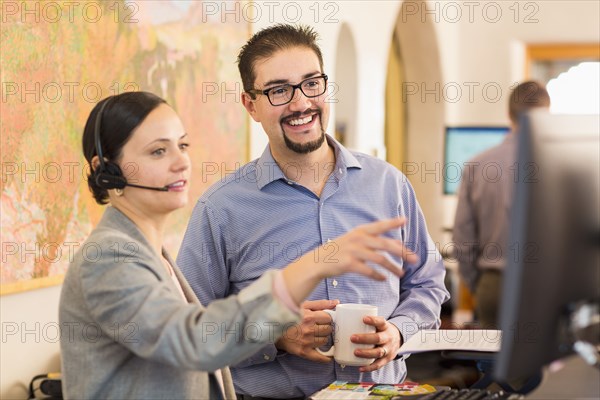 Co-workers talking in office near computer