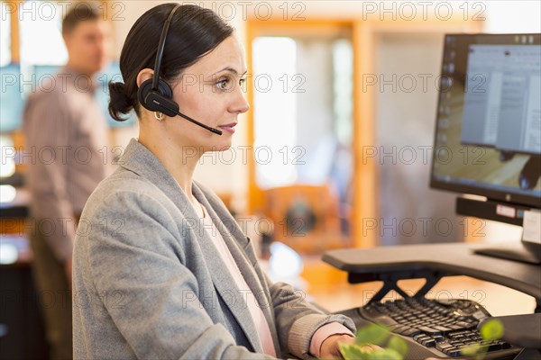 Caucasian businesswoman wearing headset using computer