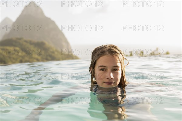 Caucasian girl swimming in infinity pool