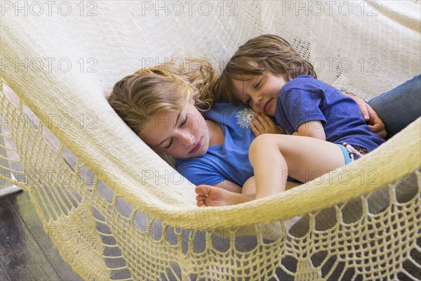 Caucasian brother and sister cuddling in hammock