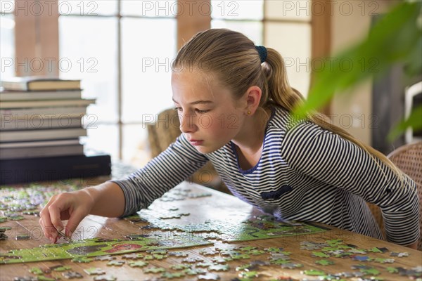 Caucasian girl solving jigsaw puzzle