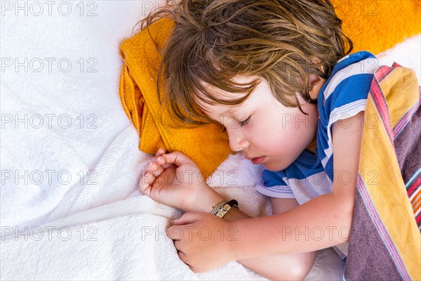 Caucasian boy laying on towels sleeping