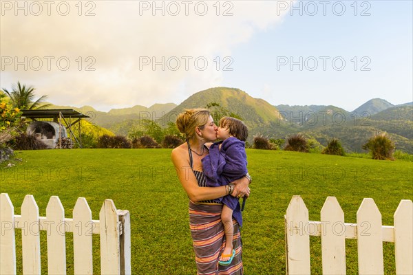 Caucasian mother carrying and kissing son