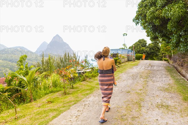 Caucasian mother carrying son on dirt path