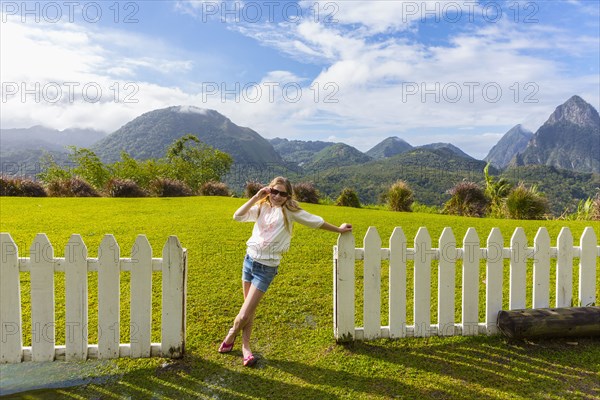 Caucasian girl wearing sunglasses leaning on fence