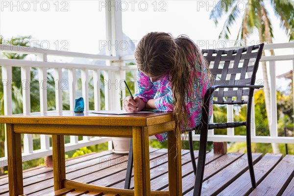 Caucasian girl sitting on balcony drawing on paper