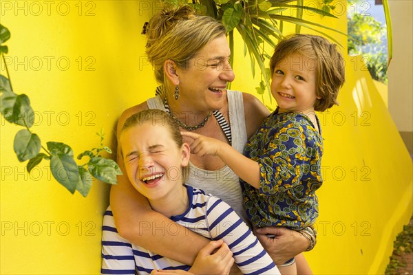 Laughing Caucasian mother hugging son and daughter