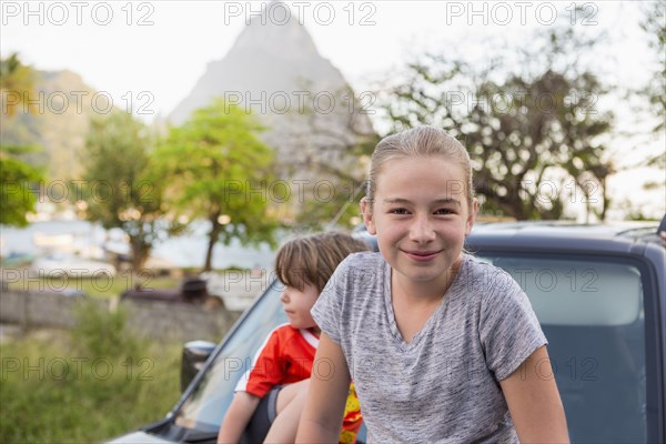 Caucasian girl and boy sitting on hood of car