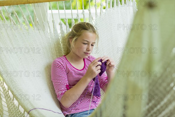 Caucasian girl laying in hammock and knitting