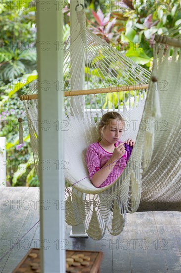 Caucasian girl laying in hammock and knitting