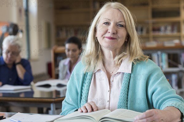 Smiling older woman reading book in library