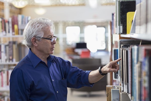 Curious Hispanic man searching for book in library