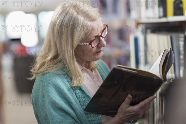 Caucasian woman reading book in library