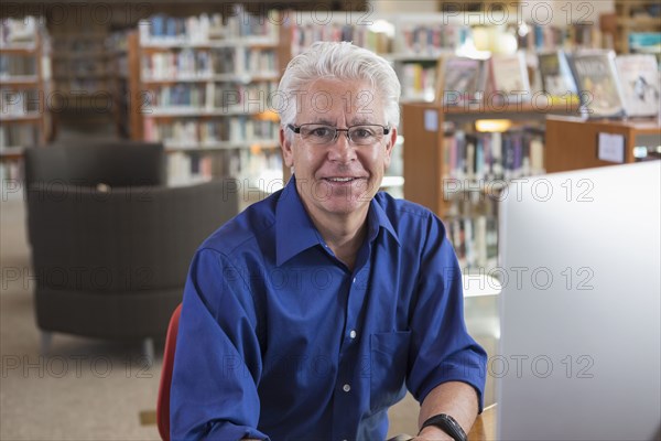 Smiling Hispanic man using computer in library