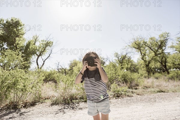 Caucasian boy photographing with camera on dirt path
