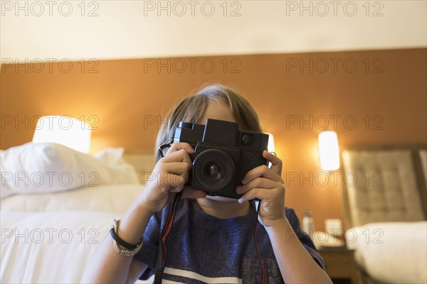 Caucasian boy photographing with camera in hotel room