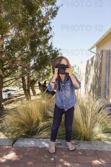 Caucasian boy photographing with camera near house