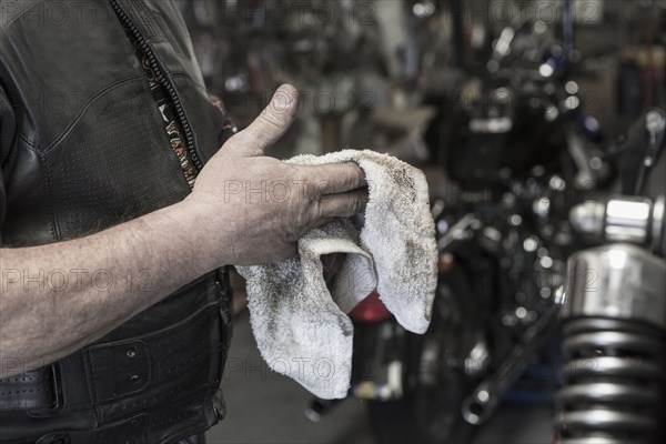 Caucasian man repairing motorcycle wiping hands