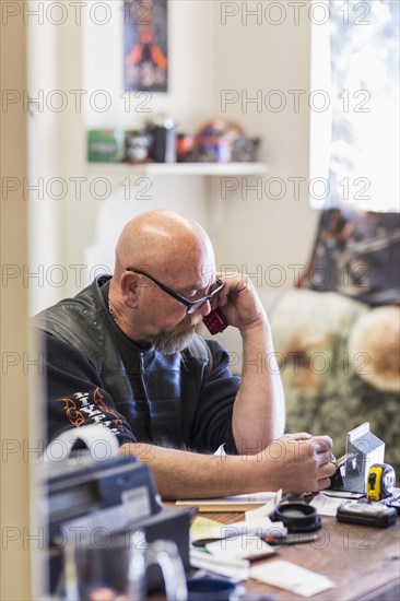 Caucasian man sitting at desk talking on cell phone
