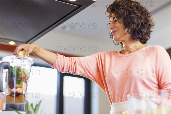 Hispanic woman preparing smoothie in blender