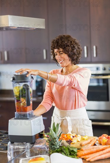 Hispanic woman preparing smoothie in blender