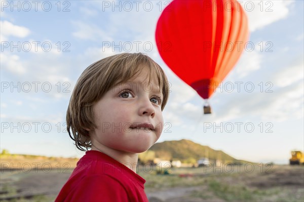 Caucasian boy under distant hot air balloon