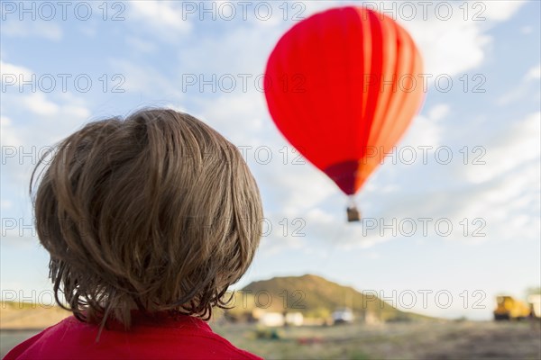 Caucasian boy watching distant hot air balloon