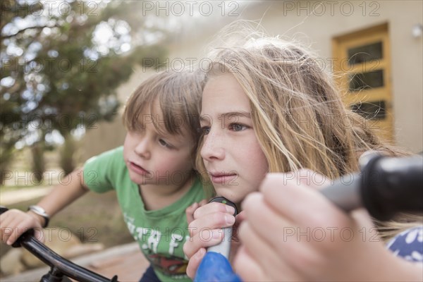 Wind blowing hair of Caucasian boy and girl on bicycles