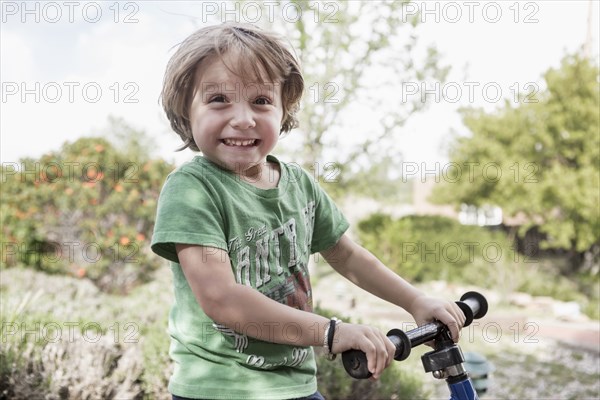 Portrait of excited Caucasian boy holding handlebars