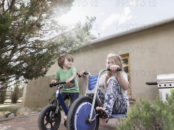 Caucasian boy and girl riding bicycles near house