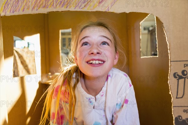 Caucasian girl playing in cardboard house