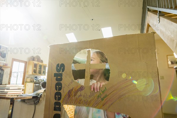 Caucasian girl playing in cardboard house