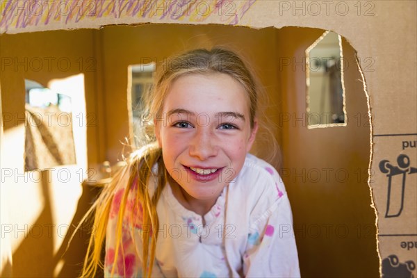 Caucasian girl playing in cardboard house