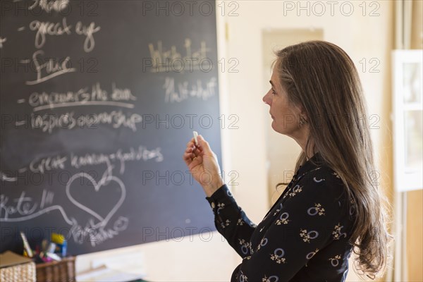 Pensive teacher holding chalk near blackboard