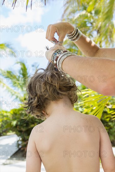 Caucasian mother cutting hair of son outdoors