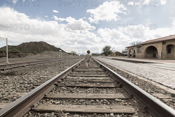 Distant Caucasian boy walking on train track