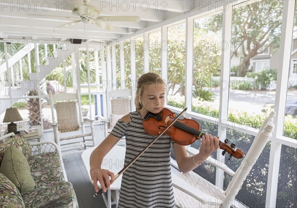 Caucasian girl playing violin on patio