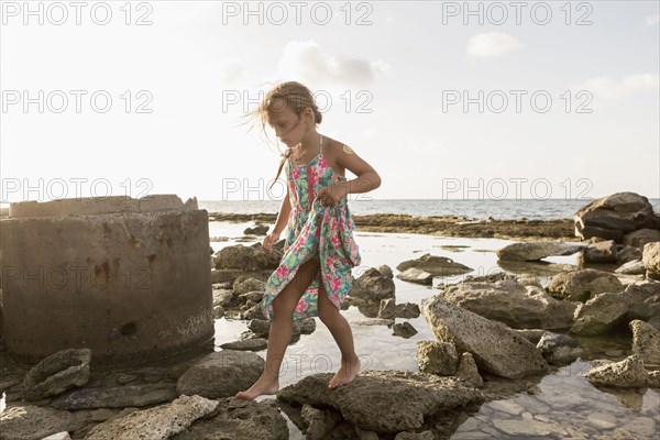 Caucasian girl walking on rocks at beach