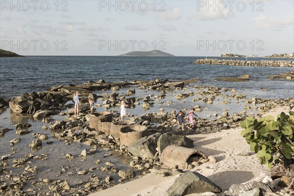 Caucasian boy and girls walking on rocks at beach